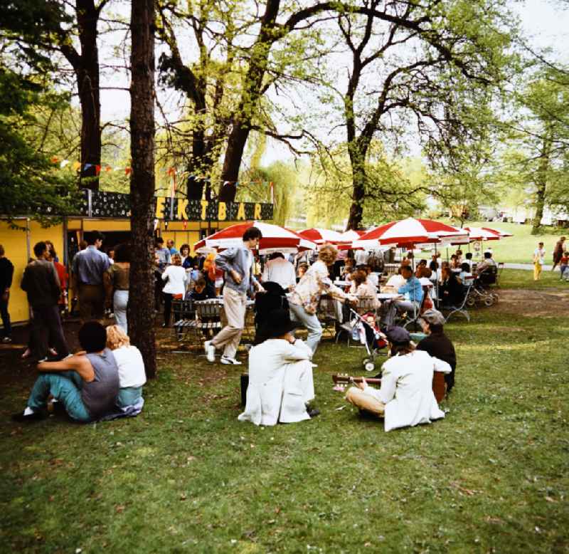 Visitors sitting together in front of the champagne bar in Volkspark Friedrichshain in Eastberlin on the territory of the former GDR, German Democratic Republic