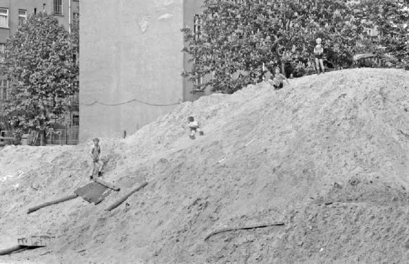 Fun and games for children and teenagers on a heap of sand on a construction site on street Corinthstrasse in Berlin Eastberlin on the territory of the former GDR, German Democratic Republic