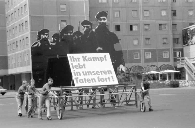 Young people push a demonstration trolley with a frame and the portrait of the revolutionary Red Sailors of the November Revolution with the poster and banner slogan 'Your fight lives on in our actions!' on Karl-Liebknecht-Strasse in Berlin East Berlin in the area of the former GDR, German Democratic Republic