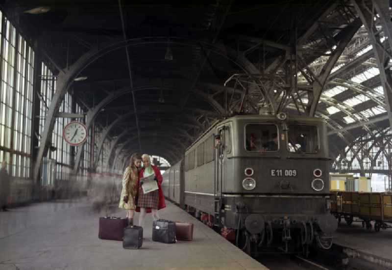 Women stand on a platform at the Ostbahnhof next to a class E 11 railcar in Berlin in the territory of the former GDR, German Democratic Republic