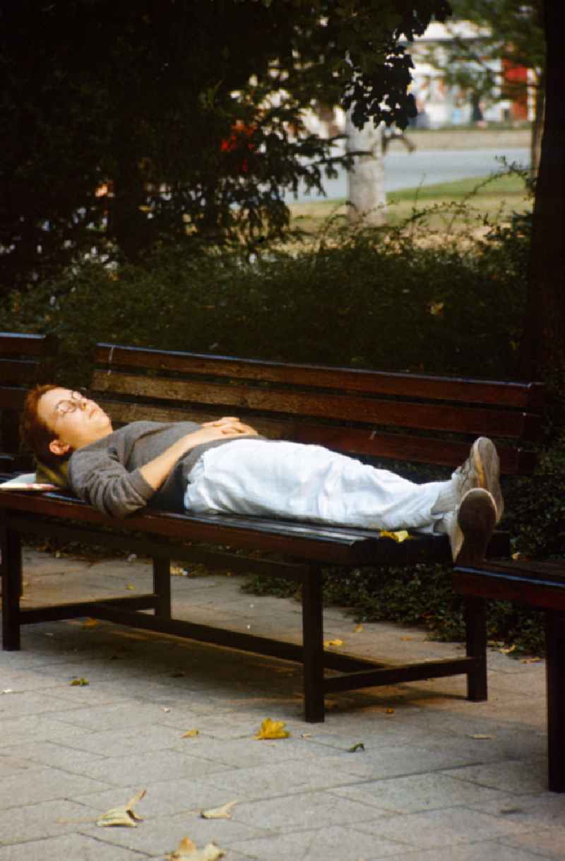 Woman sleeping on a park bench in Berlin-Mitte in the area of the former GDR, German Democratic Republic