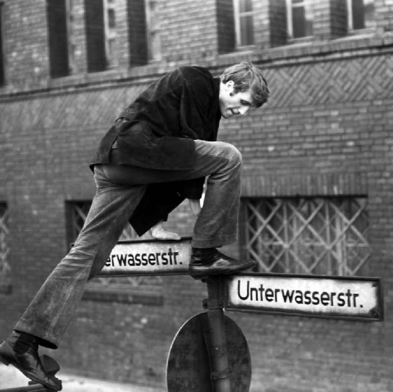 Actor Reiner Schoene climbs a street sign on the Unterwasserstrasse in Berlin-Mitte in the area of the former GDR, German Democratic Republic