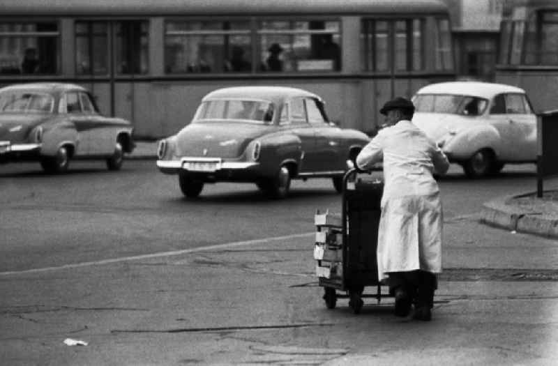 Man pushes a trolley with empty wooden boxes across the street in East Berlin in the territory of the former GDR, German Democratic Republic