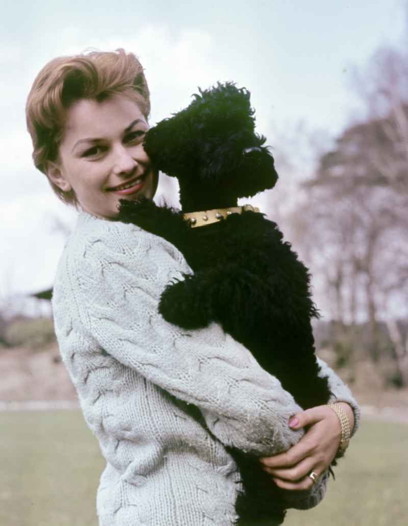 Actress Christine Laszar with poodle in the park in East Berlin on the territory of the former GDR, German Democratic Republic