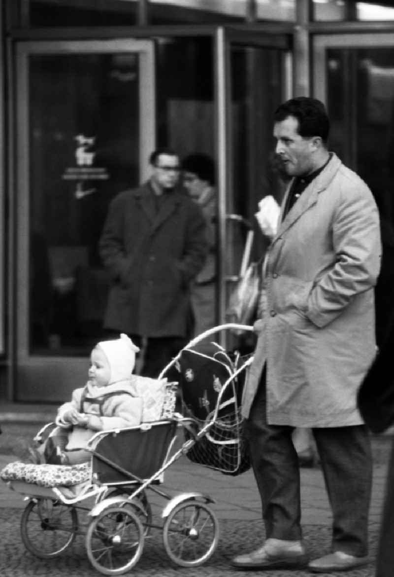 Father pushes his child in a stroller in East Berlin in the territory of the former GDR, German Democratic Republic