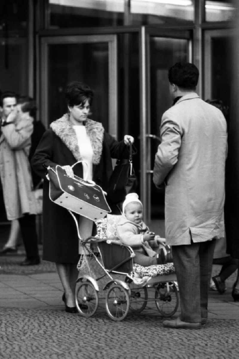 Mother and father stroll with their child in a stroller in East Berlin in the territory of the former GDR, German Democratic Republic