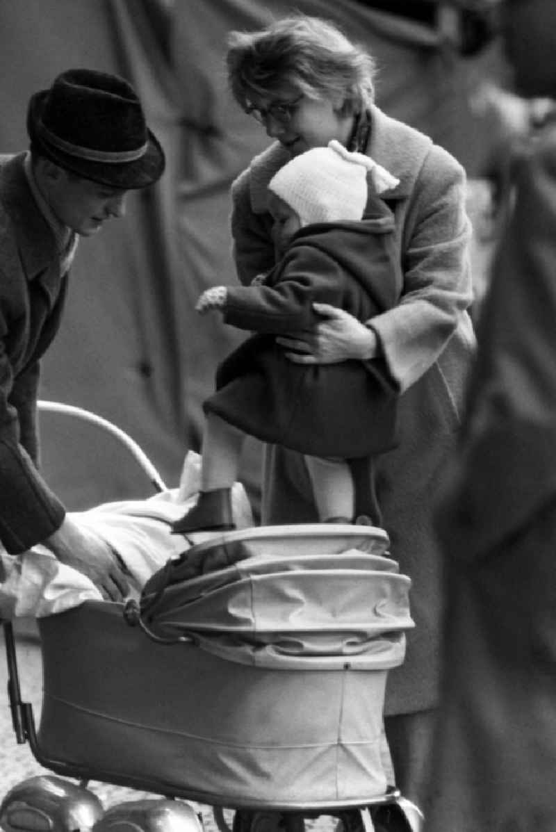 Mother puts her daughter in the stroller in East Berlin in the territory of the former GDR, German Democratic Republic