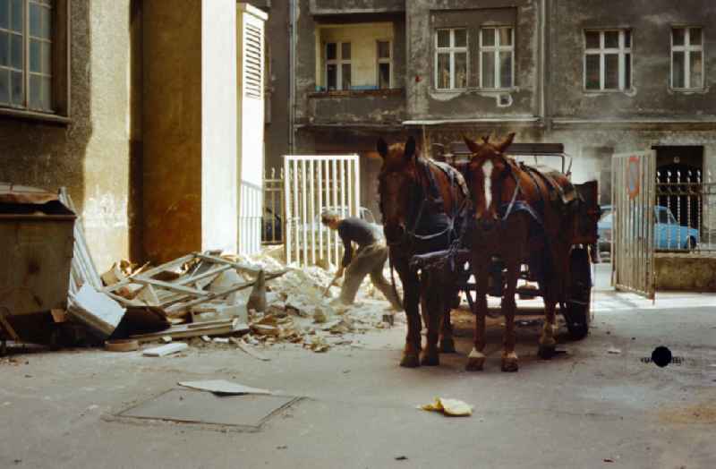 Man clears rubble from a driveway with a horse-drawn cart in East Berlin in the territory of the former GDR, German Democratic Republic