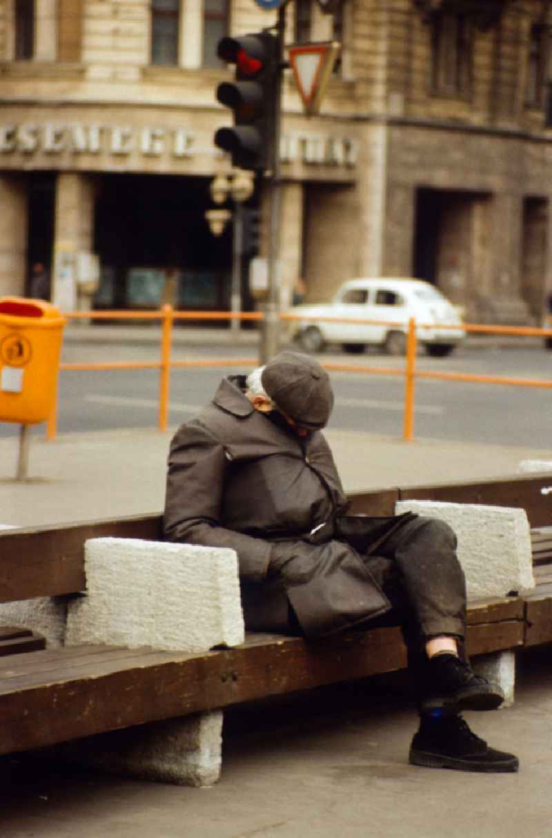 Old man sleeping on a street bench in East Berlin on the territory of the former GDR, German Democratic Republic