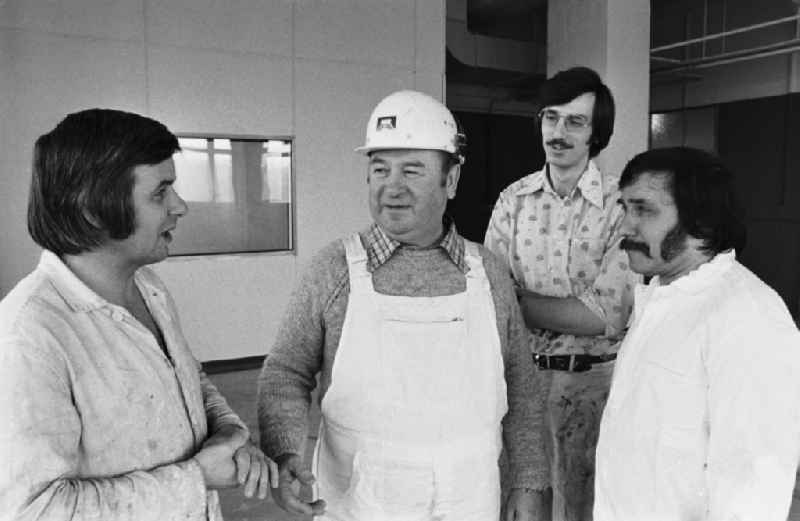 Construction workers in work clothes from a painting brigade of VEB Ausbau talking to their foreman on a construction site in a new building in the Lichtenberg district of Berlin, East Berlin in the territory of the former GDR, German Democratic Republic