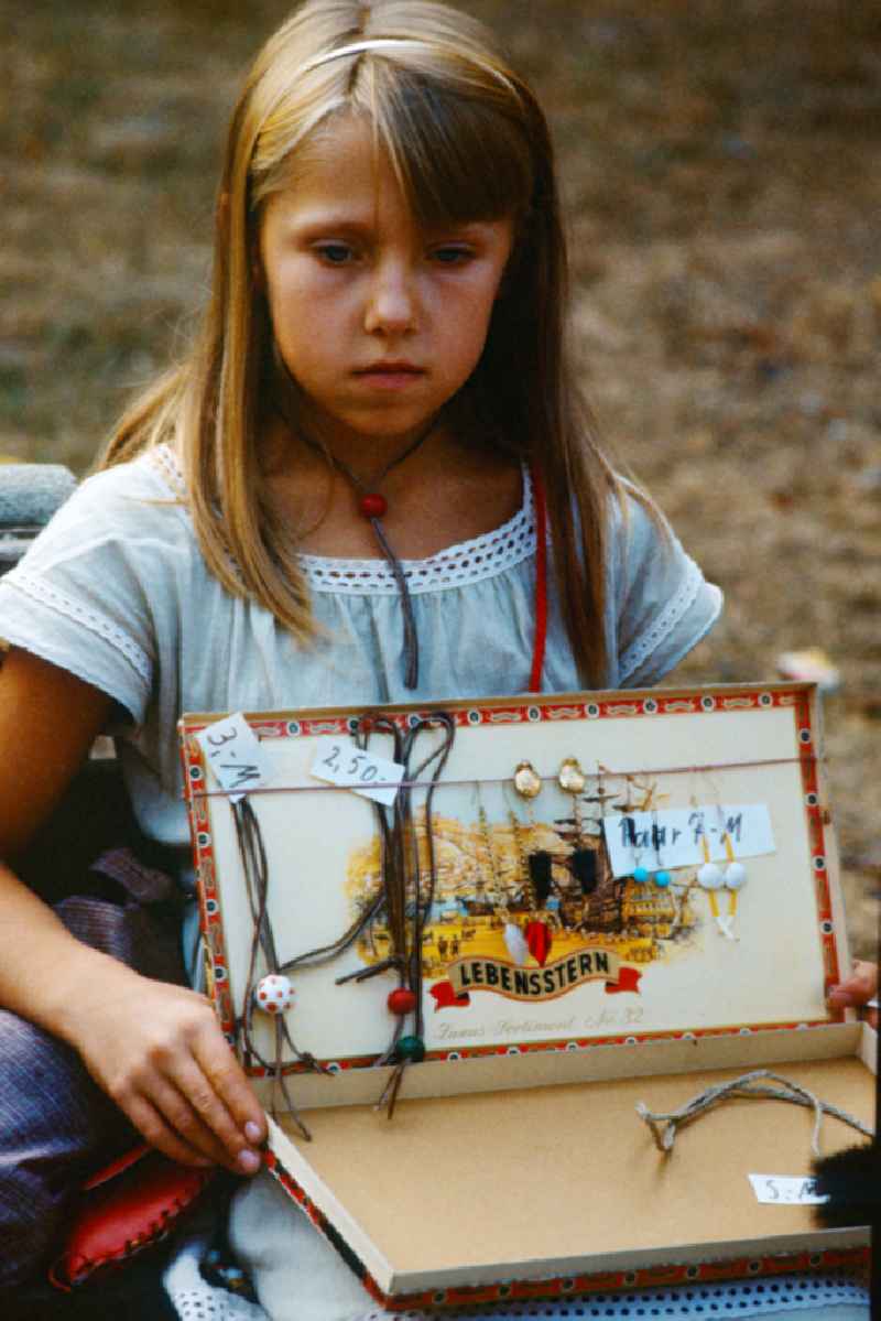 Girl sells earrings and leather necklaces in East Berlin on the territory of the former GDR, German Democratic Republic