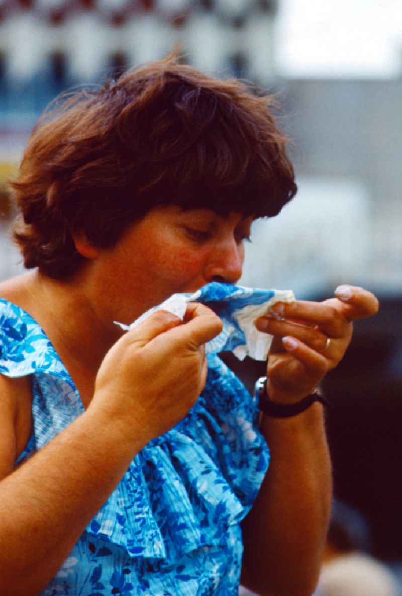 Woman cleaning her mouth with a napkin in East Berlin on the territory of the former GDR, German Democratic Republic