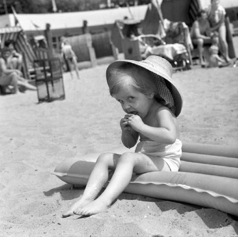 A small child with straw hat on an air mattress in the beach Müggelsee in Berlin - Köpenick. The lido Müggelsee, also known as beach Rahn village is a swimming pool in Berlin-Rahn village on the north bank of the Müggelsee