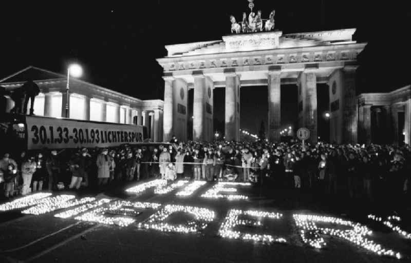 Nachtaufnahme: Lichterkette gegen Ausländerhass am Brandenburger Tor. Kerzen stehen auf Boden zusammen und bilden den Schriftzug 'NIE WIEDER'. Plakat mit der Aufschrift '30.1.33-3