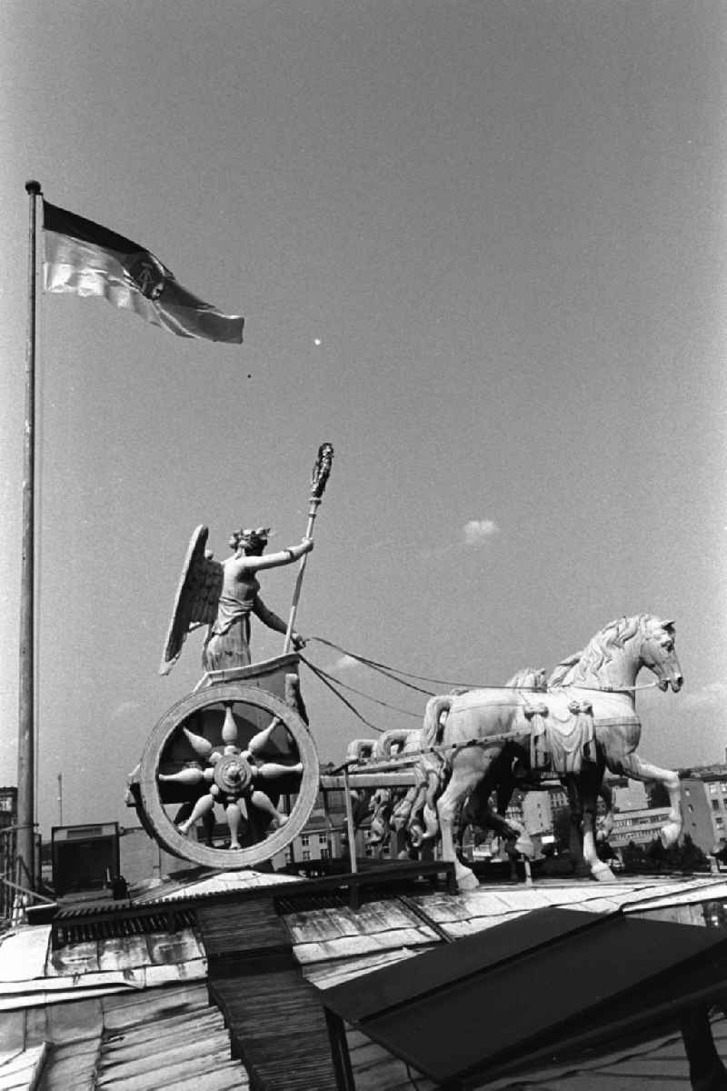 Mauerfall / Quadriga auf dem Brandenburger Tor. Wehende Fahne / Flagge der Deutschen Demokratischen Republik.