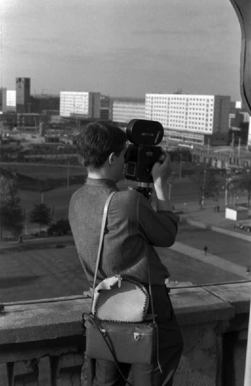 A young man standing on a balcony and filmed with a 16 mm film camera in Berlin - Mitte