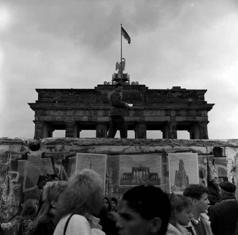 View of the Brandenburg Gate from west to east in Berlin - Mitte. A border guard of DDR running on the Berlin Wall