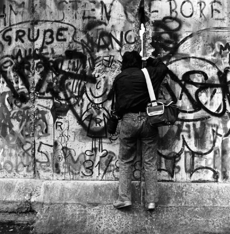 A photographer photographed through a crack in the Berlin Wall in Berlin