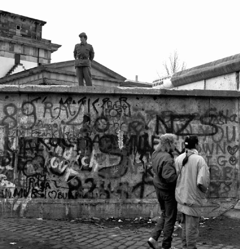 A soldier of the GDR border troops on the Berlin Wall at the Brandenburg Gate in Berlin. To provide some degree of order, border guards were posted on the wall. You should prevent the wall from too euphoric 'frontier workers' is climbed
