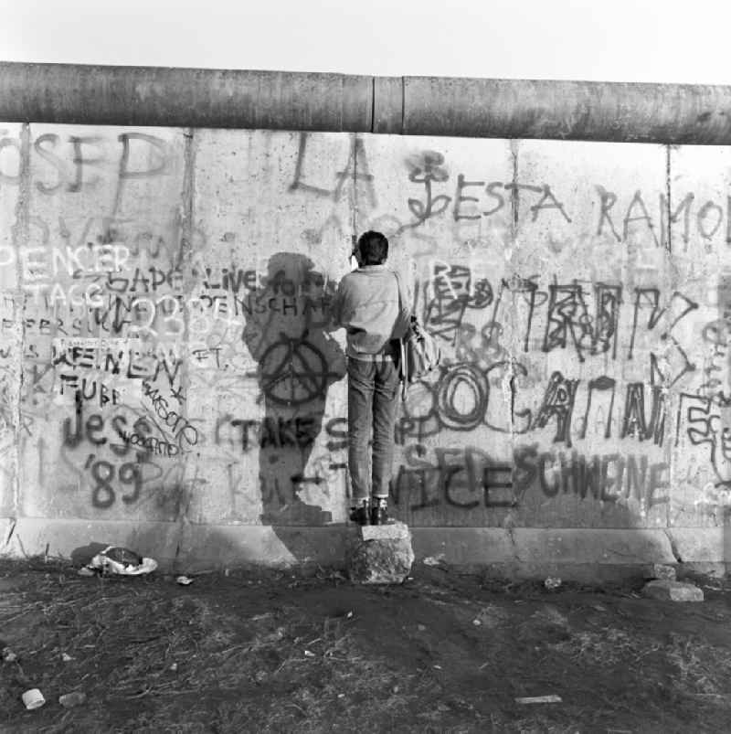 A man photographs through a crack in the Berlin Wall in Berlin