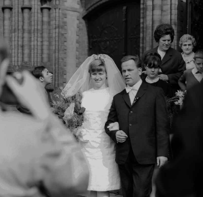 A happy wedding couple in front of the Immanuel Church in Berlin - Prenzlauer Berg. The Socialist marriage has been touted since the 195