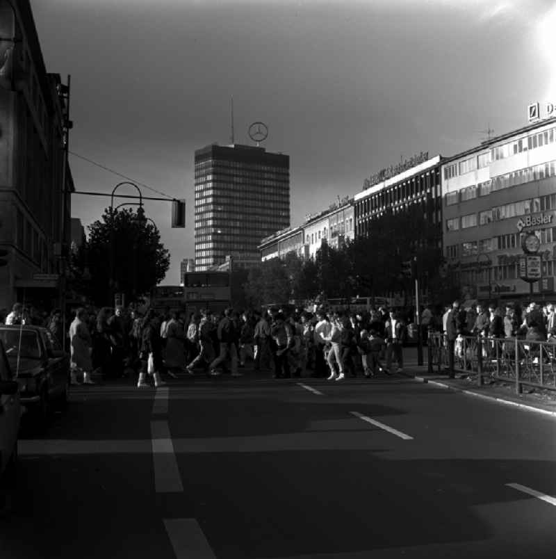 Pedestrians cross the Tauentzienstrasse in Berlin. In the background is the Europe Center. Landmark Europa-Center is a highly recognizable Mercedes star on the roof of the office tower