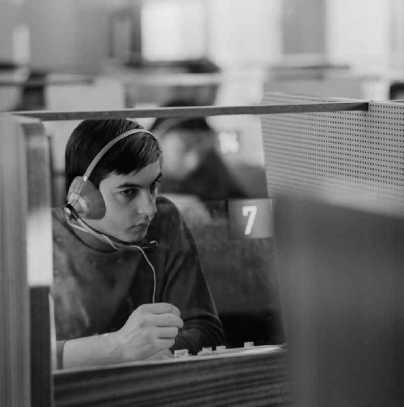 A young man sits in the Cabinet of language in a booth with headphones in Berlin - Weissensee. A speech Cabinet, also called language lab, is a specially equipped room for learning languages??. He is the active exercise of speaking and understanding