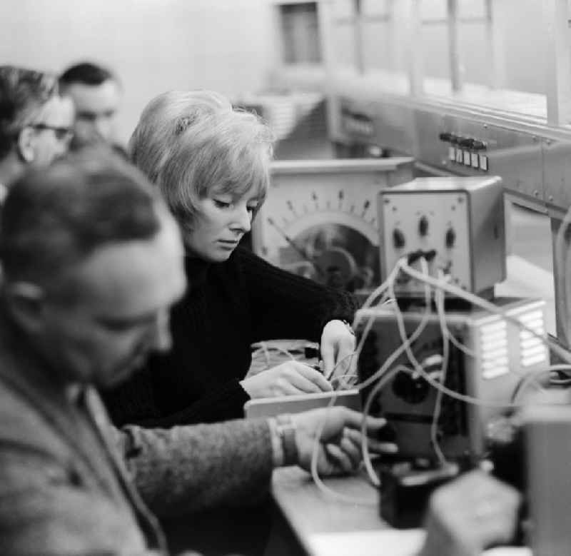 A young woman sitting with colleagues during a training in physics in Berlin Cabinet. Here in a test set with different devices. In the background, a review - voltmeter to measure various electronic voltages