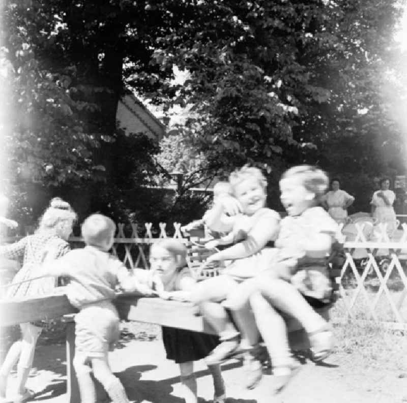 Kinder / Kleinkinder spielen am Karussell auf Kindergarten-Spielplatz.