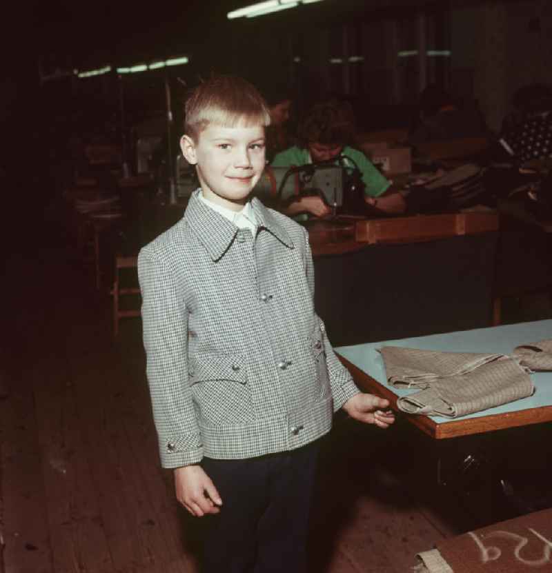 Ein Junge präsentiert in einem VEB Kindermoden einen Anzug der aktuellen Kollektion.