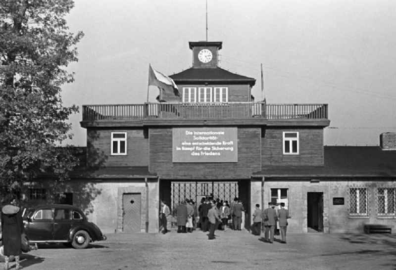 Besucher betreten durch das Torgebäude das Gelände des ehemaligen Konzentrationslager Buchenwald. Über dem Tor hängt die Losung 'Die Internationale Solidarität - eine entscheidende Kraft im Kampf für die Sicherung des Friedens'. Zwei Jahre später erfolgte die Einweihung als Nationale Mahn- und Gedenkstätte Buchenwald. In den 5