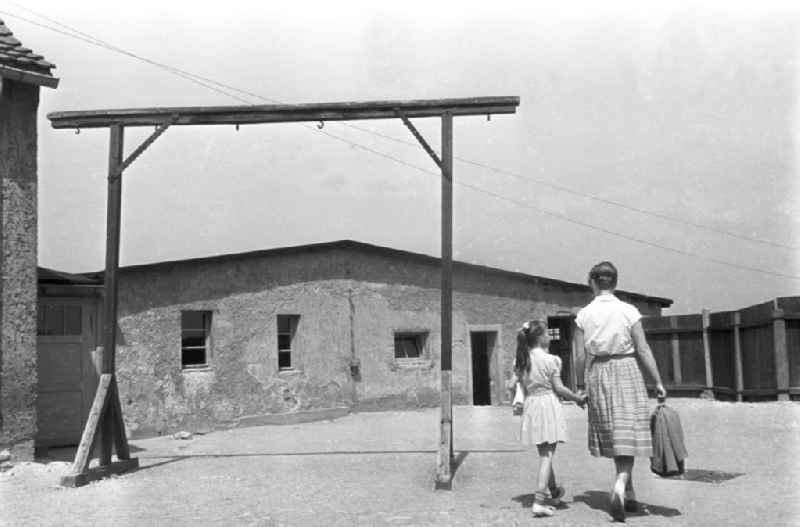 Eine Frau und ihre Tochter besuchen die Nationale Mahn- und Gedenkstätte Buchenwald. Sie gehen an einem Galgen vorbei auf eine ehemalige Barracke zu.  Das ehemalige Konzentrationslager Buchenwald wurde 1958 als Nationale Mahn- und Gedenkstätte eingeweiht. Beste Bildqualität nach Vorlage!