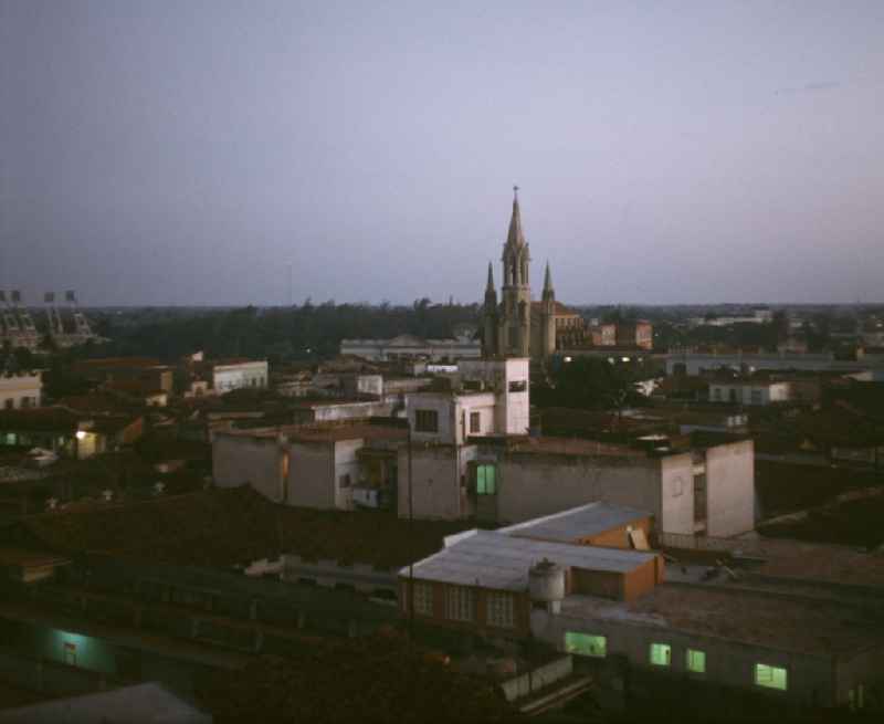 Blick über die Dächer der drittgrößten Stadt Kubas, Camagüey, auf die Kirche Iglesia Sagrada Corazon de Jesus. Im Hintergrund das Estadio Cándido González (l).