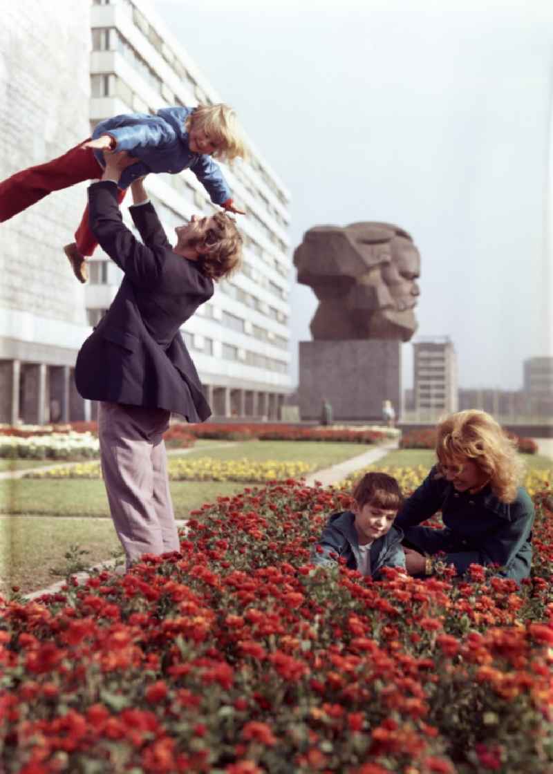 Young family walks in the park at the monument of the Karl-Marx-Monument of the Brueckenstrasse in the district Zentrum in Chemnitz - Karl-Marx-Stadt in the state Saxony in the area of the former GDR, German Democratic Republic