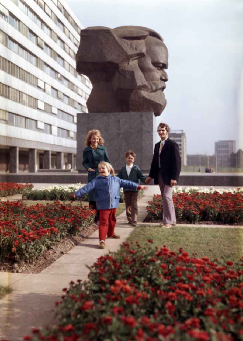 Young family walks in the park at the monument of the Karl-Marx-Monument of the Brueckenstrasse in the district Zentrum in Chemnitz - Karl-Marx-Stadt, Saxony in the area of the former GDR, German Democratic Republic