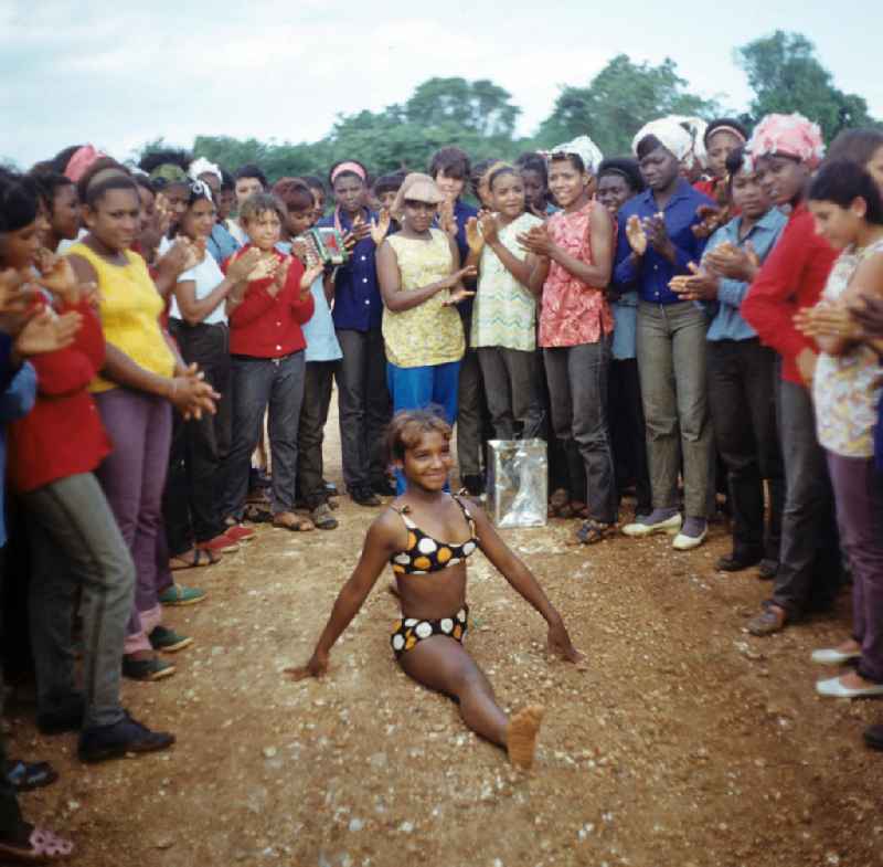 Zum Ernteeinsatz haben sich kubanische jugendliche Mädchen in einem Camp in der Provinz Ciego de Ávila in Zentral-Kuba zusammengefunden - in der Pause präsentiert ein Mädchen unter dem Klatschen der anderen ihr tänzerisches Können. Girls as harvest hand in a Girls-Camp in the province Ciego de Ávila - Cuba.