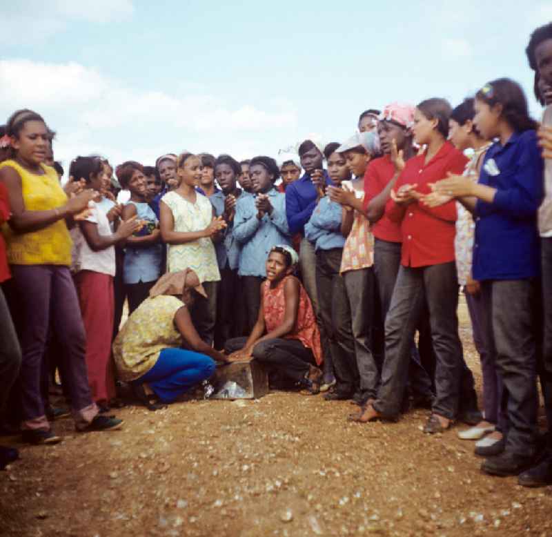 Zum Ernteeinsatz haben sich kubanische jugendliche Mädchen in einem Camp in der Provinz Ciego de Ávila in Zentral-Kuba zusammengefunden - in der Pause sorgen die Mädchen mit Gesang und improvisierter Trommel für Unterhaltung. Girls as harvest hand in a Girls-Camp in the province Ciego de Ávila - Cuba.