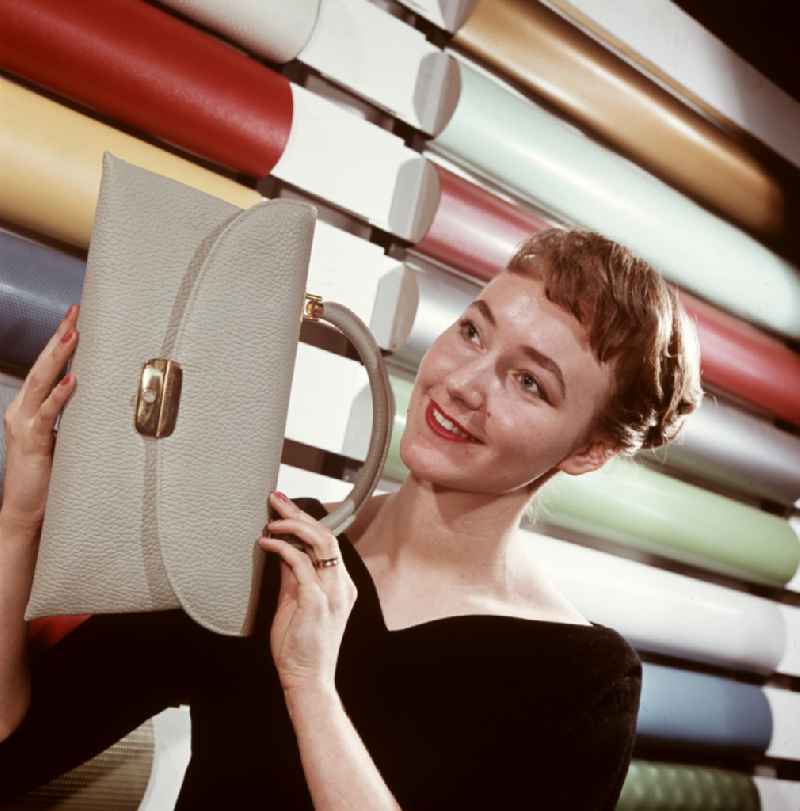 A woman presents a bag made of synthetic leather from VEB Cowaplast-Werke Coswig, Saxony in the territory of the former GDR, German Democratic Republic