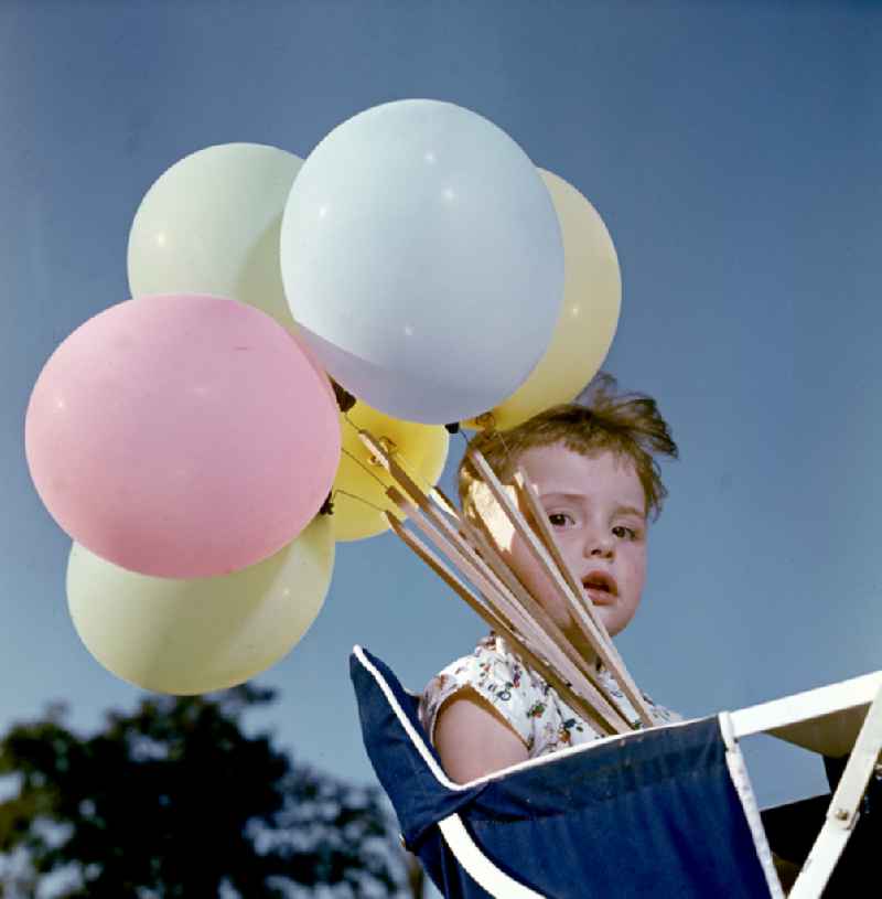 Girl with balloons in a stroller in Coswig, Saxony in the territory of the former GDR, German Democratic Republic