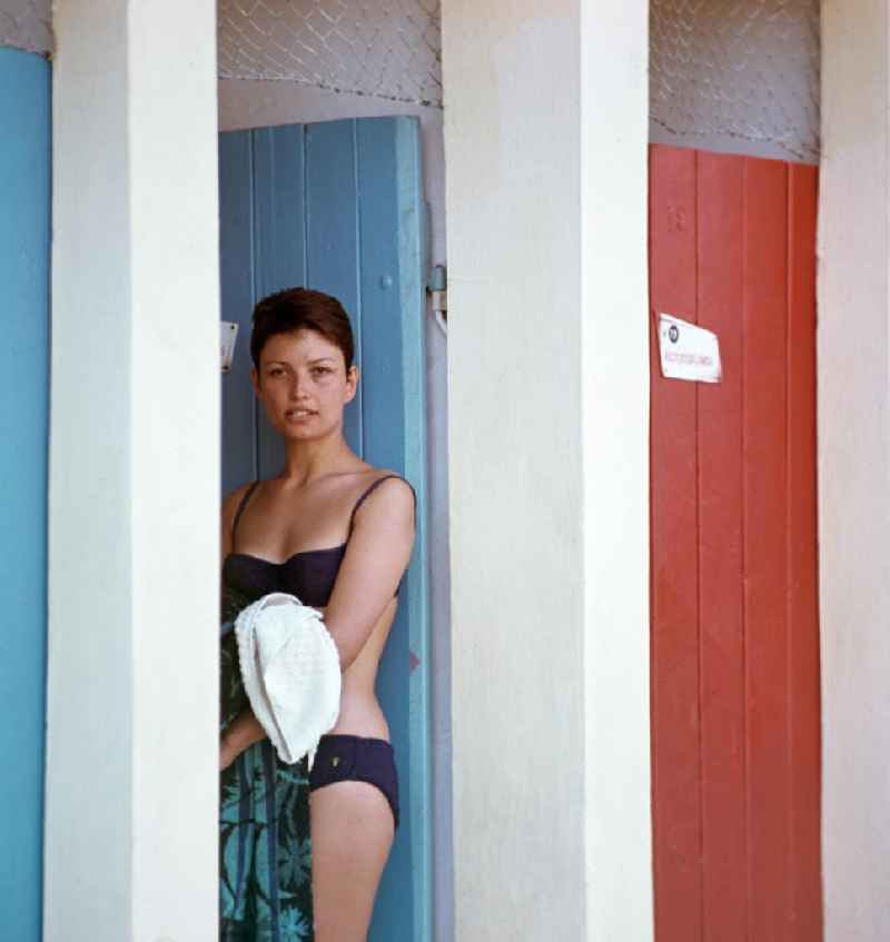 Eine junge Frau im Bikini steht an einer Tür zur Umkleidekabine im Stadtbad Debrecen, heute gehört es zum Wellnesbereich einer Hotelanlage.