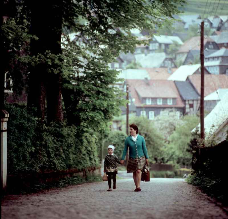 Eine Frau geht mit ihrer Tochter auf einer Straße in Deesbach im Thüringer Wald. Der Thüringer Wald mit seinen Wander- und Erholungsmöglichkeiten war ein beliebtes Urlaubsziel in der DDR.