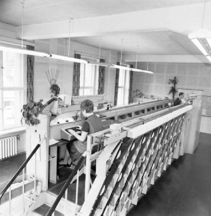 Blick in das Briefzentrum Dresden. Zwei Mitarbeiter sitzen an Brief-Sortiermaschine.
