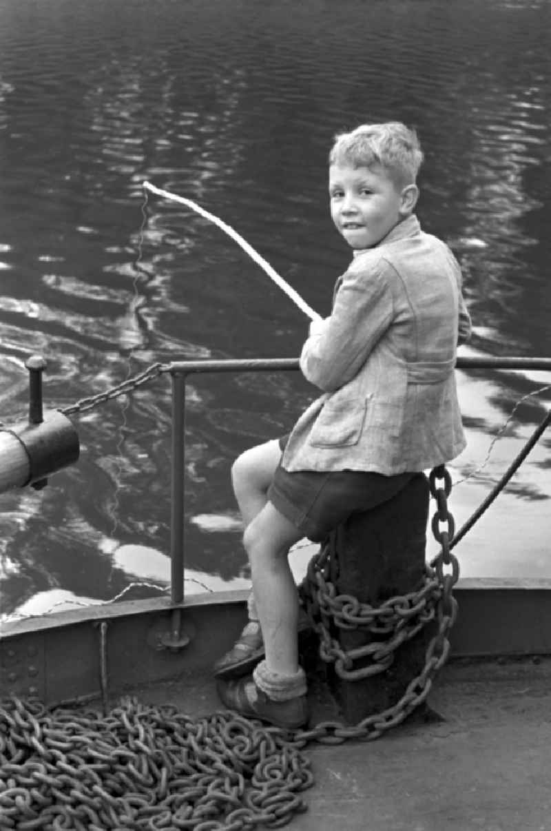 Enduring fishing with a hand fishing rodby a little boy on street Terrassenufer in Dresden, Saxony on the territory of the former GDR, German Democratic Republic