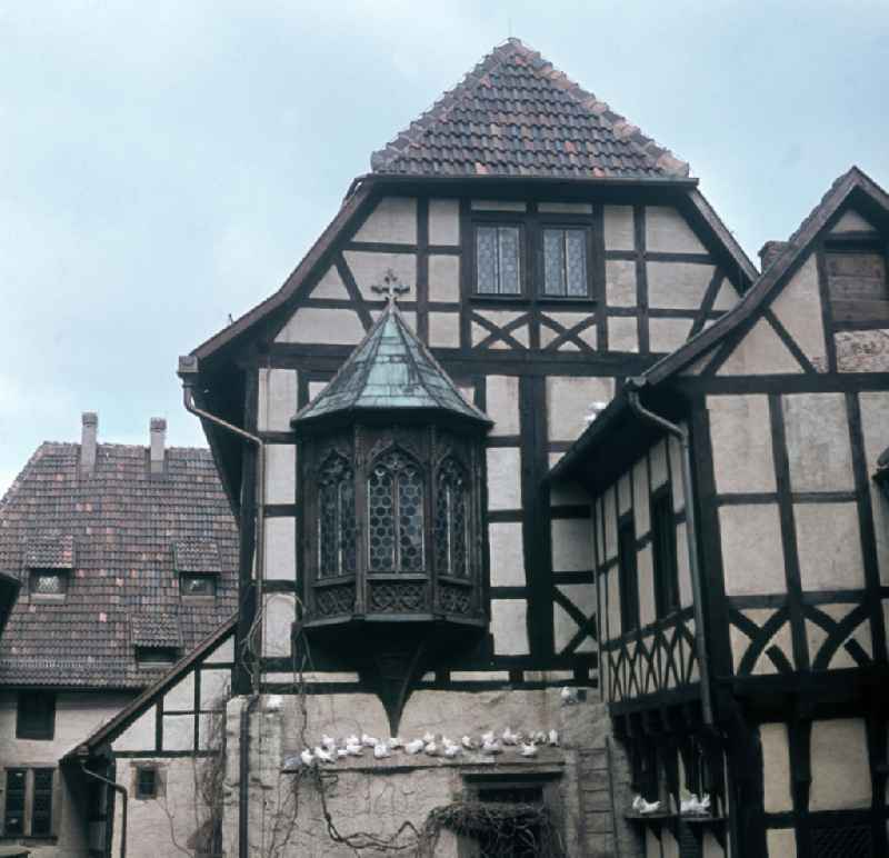 Ein Gebäude mit Erker auf dem Burghof der Wartburg. Auf einem Vorsprung hat sich eine Schar Tauben versammelt. Der Legende nach wurde die Wartburg im Jahre 1067 von Graf Ludwig dem Springer gegründet, erstmals erwähnt wurde sie im Jahre 108