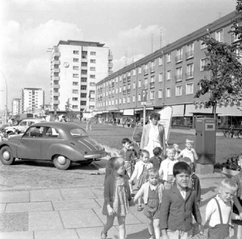Kindergarten-Kinder gehen in der Gruppe auf der Lindenallee spazieren, Auto / Wartburg DKW F9 steht im Hintergrund.