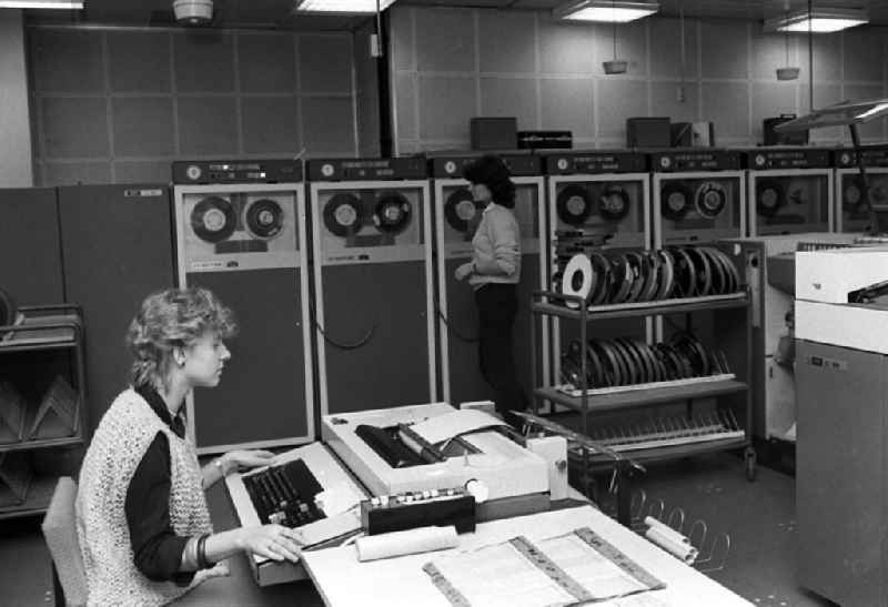 Zwei junge Frauen in einem Datenverarbeitungsbetrieb VEB Robotron-Optima Erfurt. Eine Frau sitzt an Schreibgerät / Schreibmaschine und eine stehet an Abspieleräten für Magnetbänder.