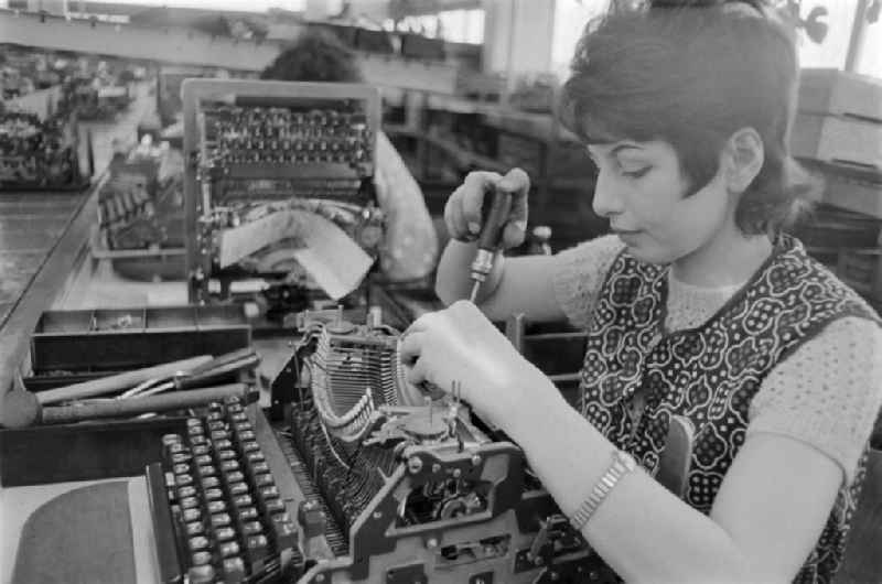 A young worker working with a typewriter in the VEB Optima Bueromaschinenwerk Erfurt in Thuringia