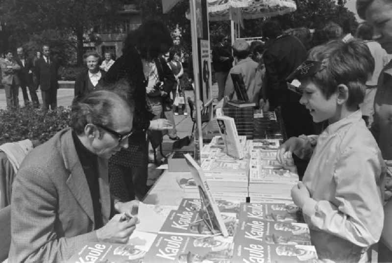 Writers' bazaar on the grounds of the IGA in the Rose Garden on the occasion of the 15th Workers' Festival in Erfurt in the federal state of Thuringia in the territory of the former GDR, German Democratic Republic. Alfred Wellm ( known in the GDR mainly as a children's author ) signs his book ' Kaule ' for a boy at the book bazaar