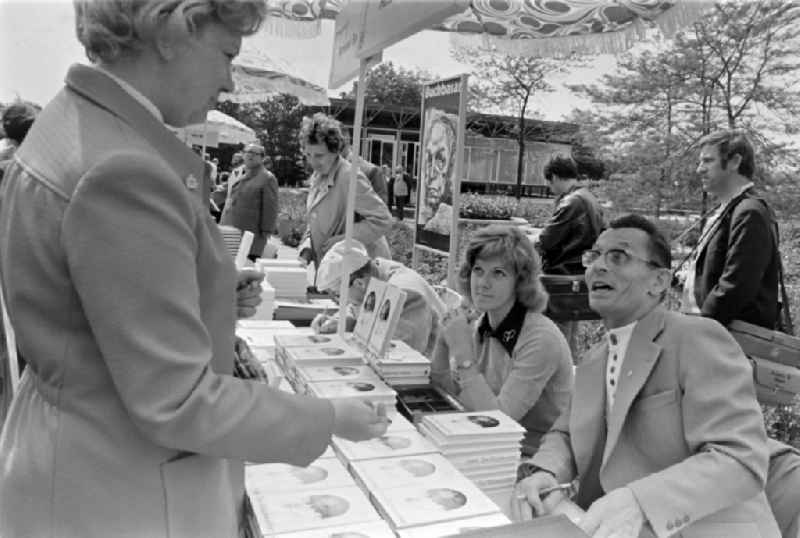 Writers' bazaar on the grounds of the IGA in the Rose Garden on the occasion of the 15th Workers' Festival in Erfurt in the federal state of Thuringia in the territory of the former GDR, German Democratic Republic. Herbert Jobst (author) signs his book ' Der Gluecksucher ' at the book bazaar. In the background the writer Bernhard Seeger