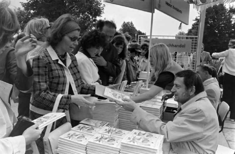 Writers' bazaar on the grounds of the IGA in the Rose Garden on the occasion of the 15th Workers' Festival in Erfurt in the federal state of Thuringia in the territory of the former GDR, German Democratic Republic. Heinz Knobloch ( author and feature writer ) signs one of his books at the book bazaar